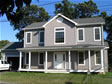 A low & wide country front porch with large rounded columns enhances the front elevation of this home